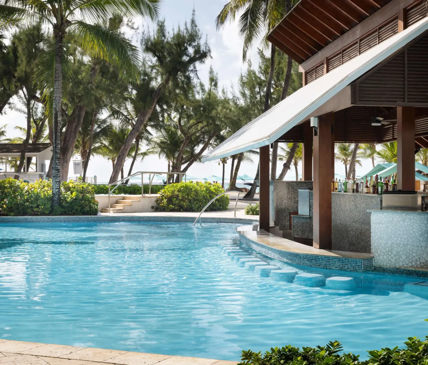 Resort pool with swim-up bar and palm trees at Sandals Barbados.