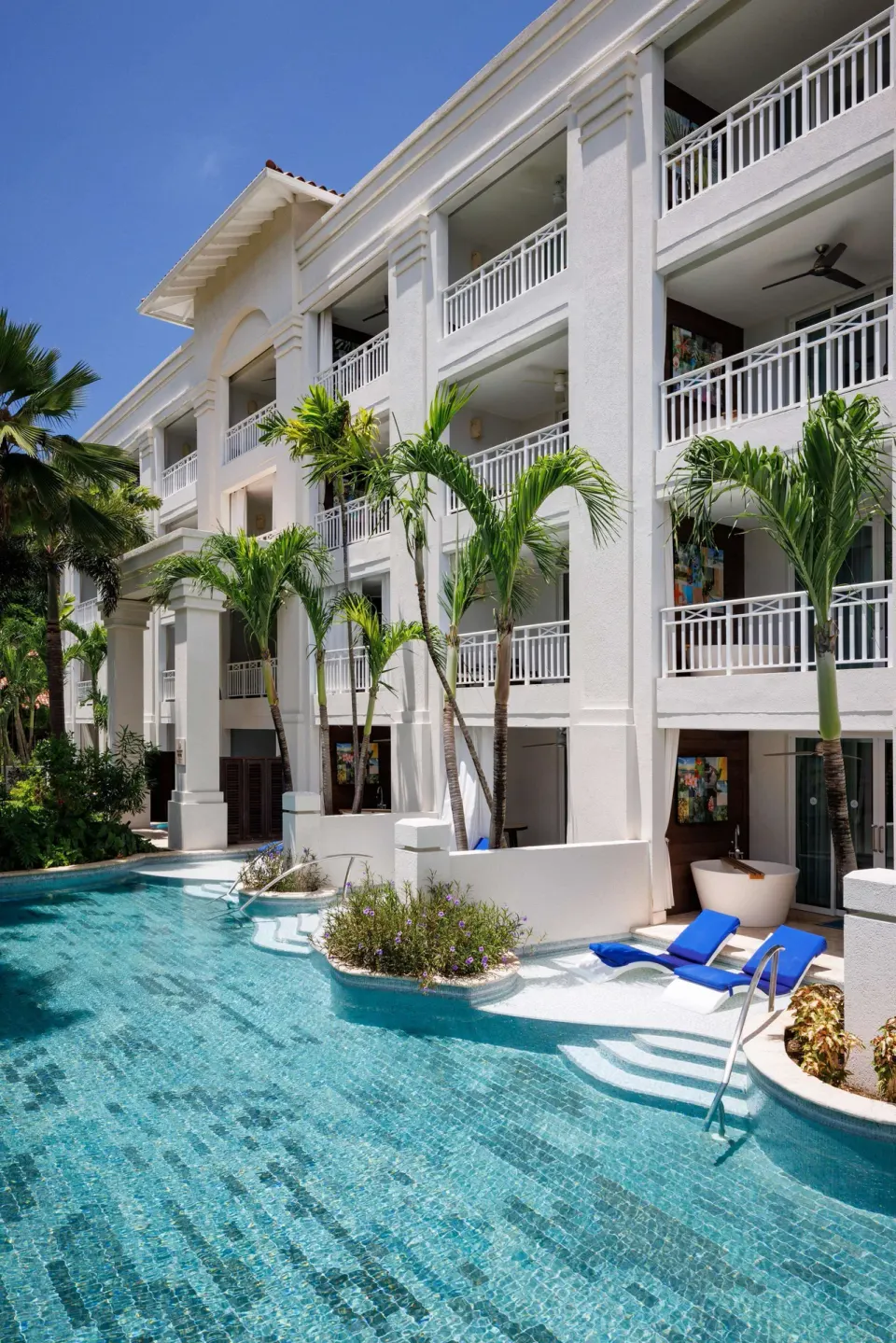 Swim-up pool beside balconies and palm trees at Sandals Barbados.