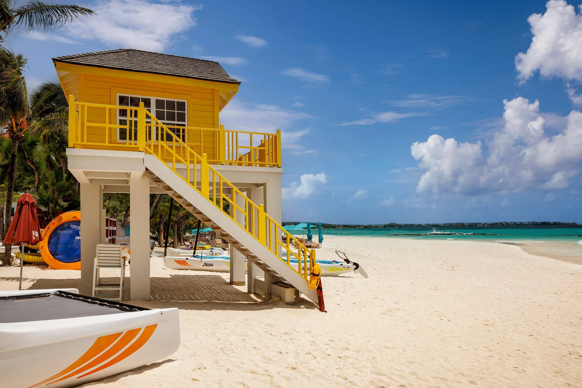 Yellow beach hut with stairs and watercraft on the sand at Sandals Barbados.
