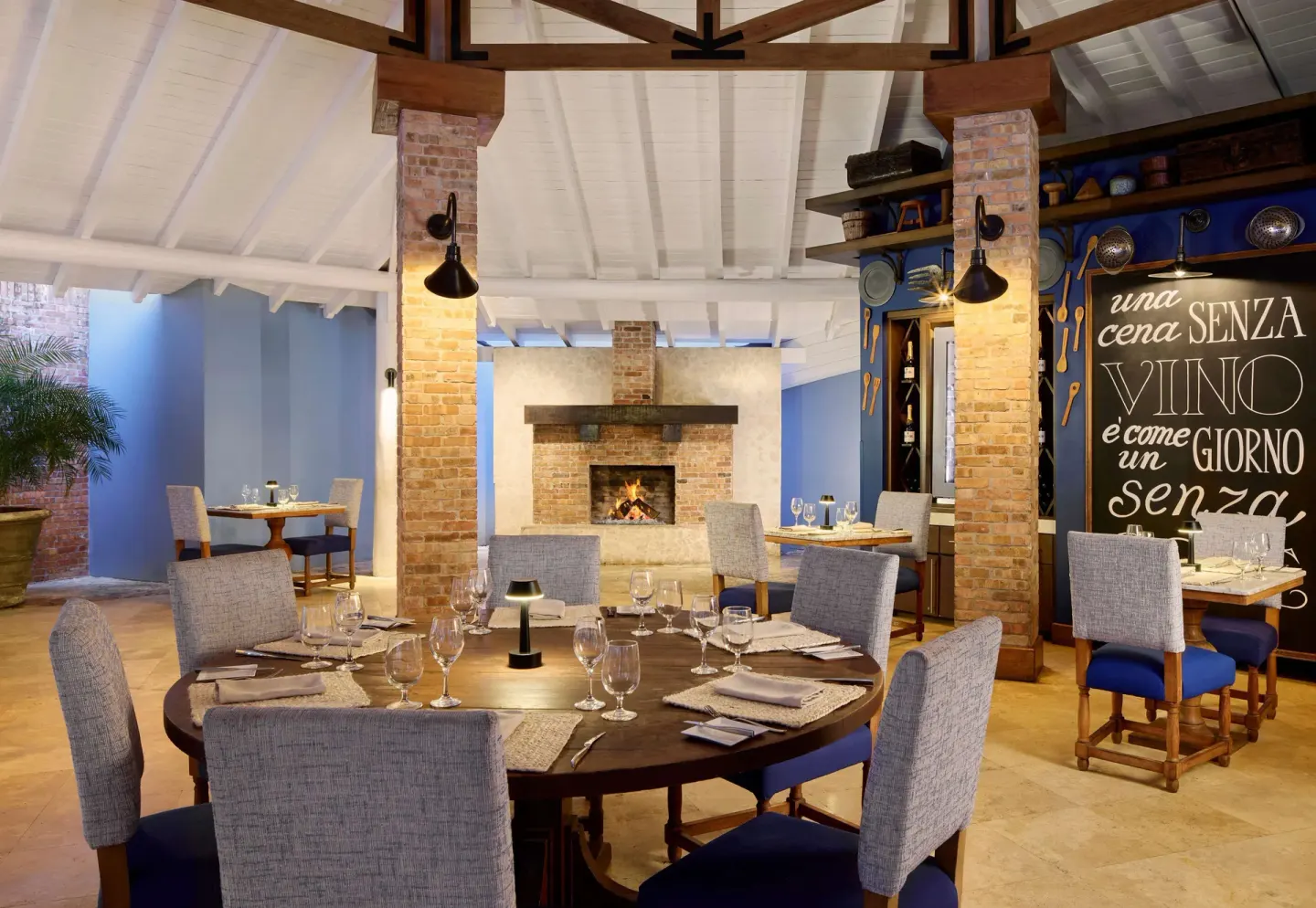Portofino's dining room with brick fireplace and Italian wall text at Sandals Barbados.