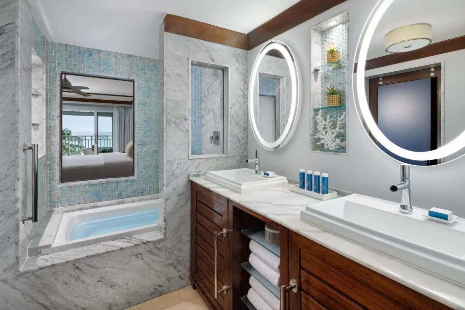 Club Penthouse bathroom with vanity mirrors and tub at Sandals Barbados.
