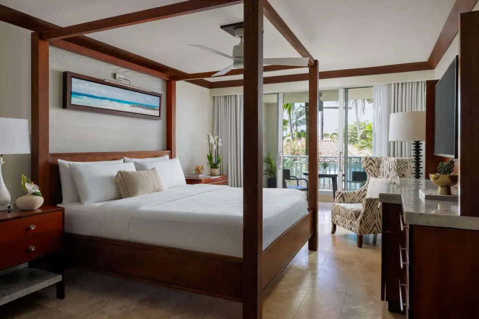 Four-poster king bed and balcony view in a Luxury Room at Sandals Barbados.