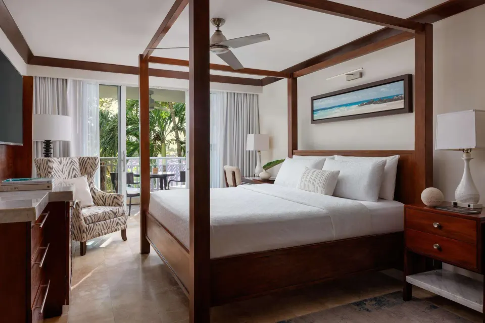 Caribbean Grand Luxe king bedroom with balcony and garden greenery at Sandals Barbados.