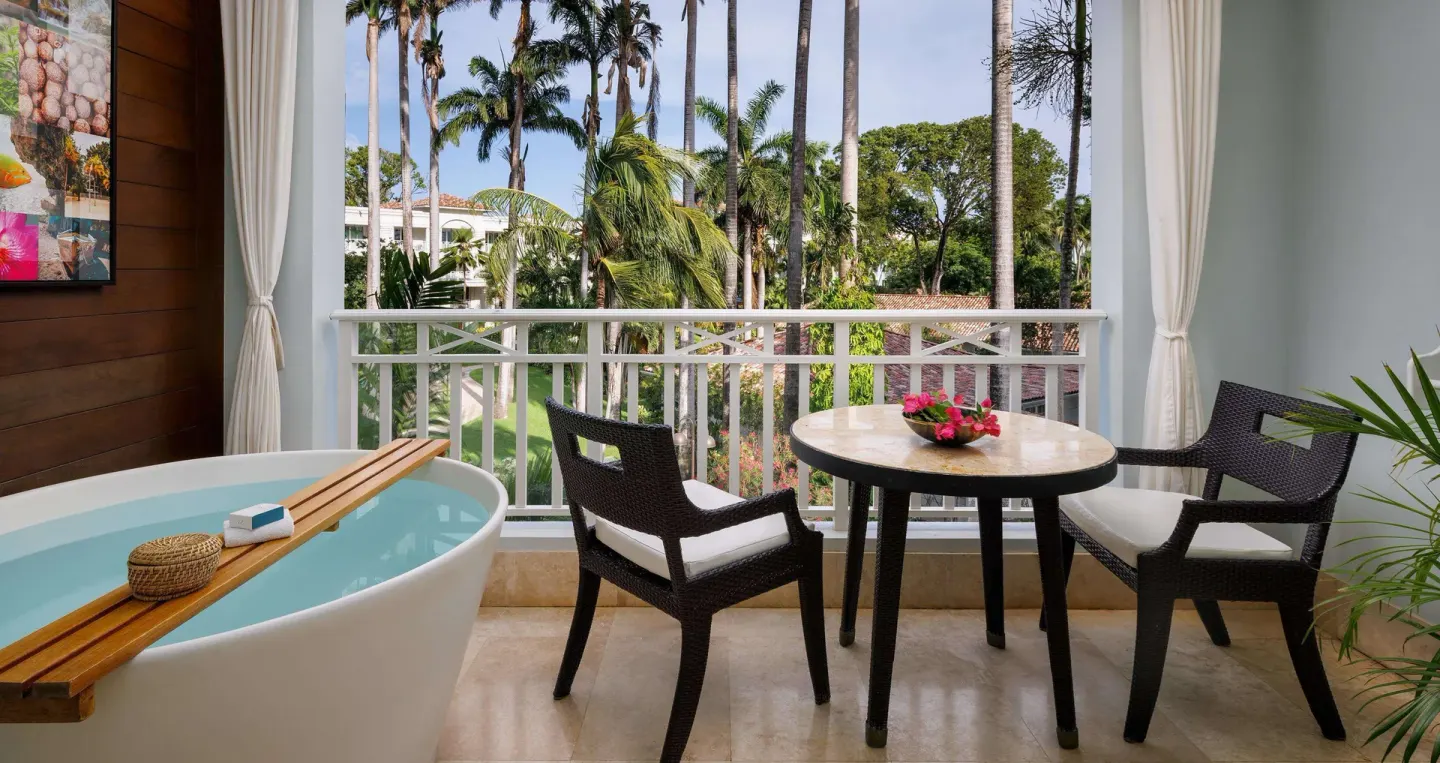 Covered balcony with soaking tub and garden view at Sandals Barbados.