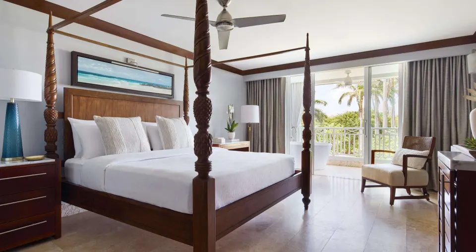 Spacious king bedroom with balcony seating and palm view at Sandals Barbados.
