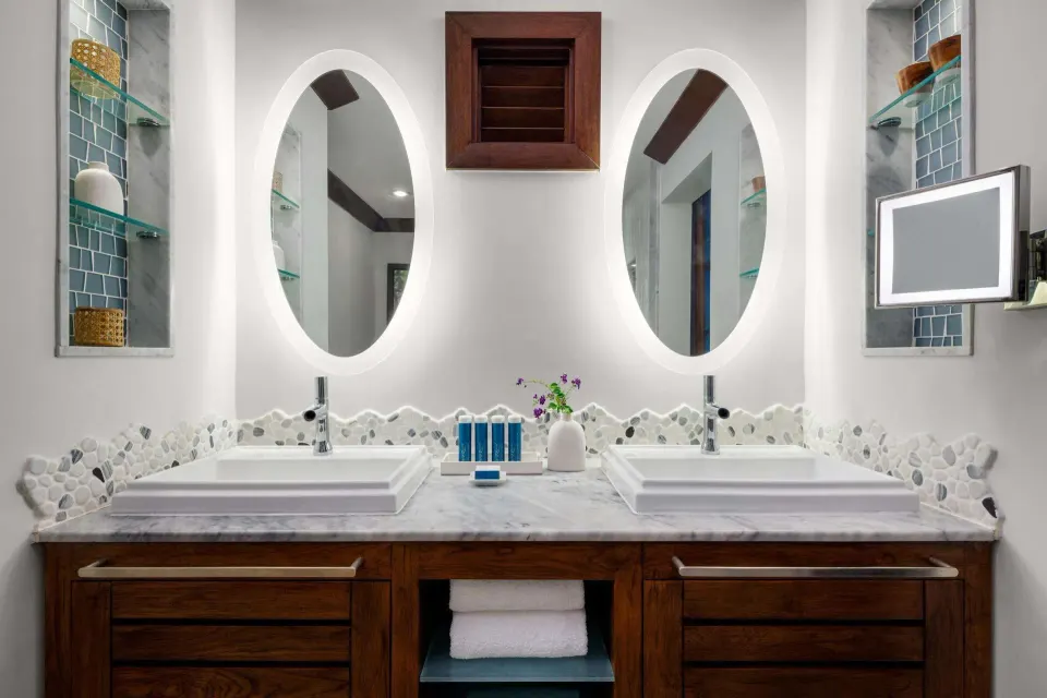 Double vanity with oval mirrors and mosaic backsplash at Sandals Barbados.