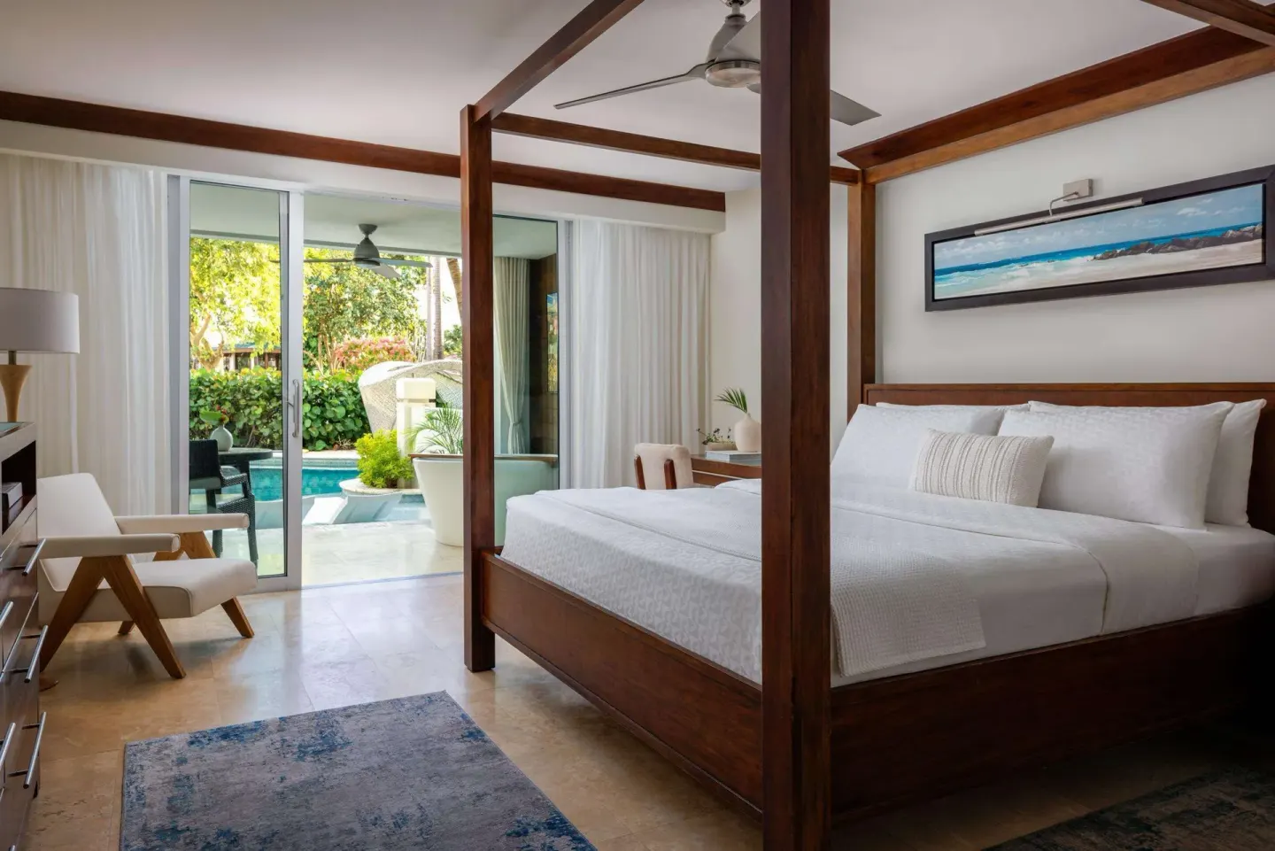 Four-poster king bed in a luxury room opening to greenery and water at Sandals Barbados.