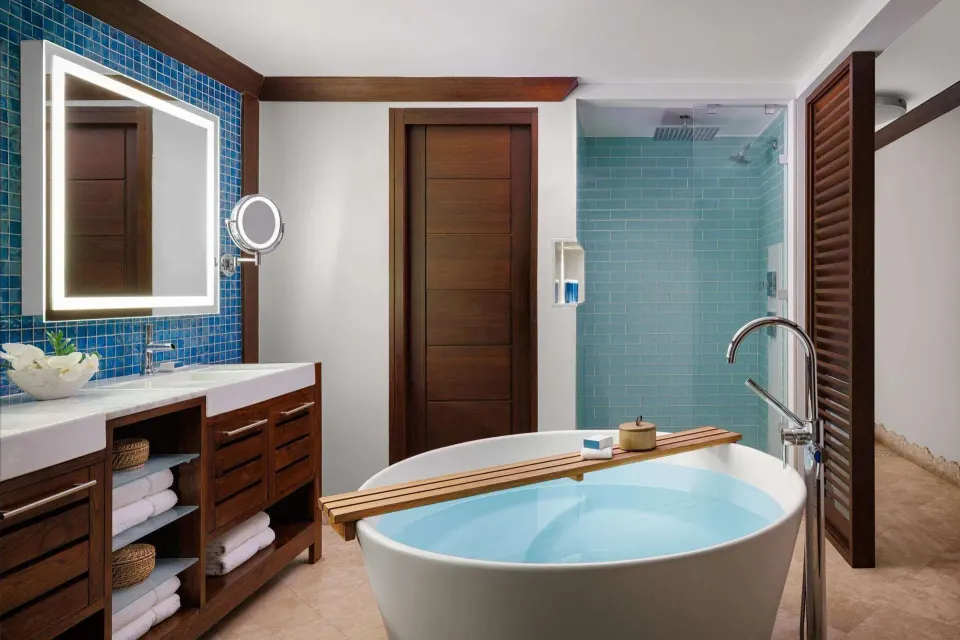 Bathroom with soaking tub and blue-tile shower in a suite at Sandals Barbados.