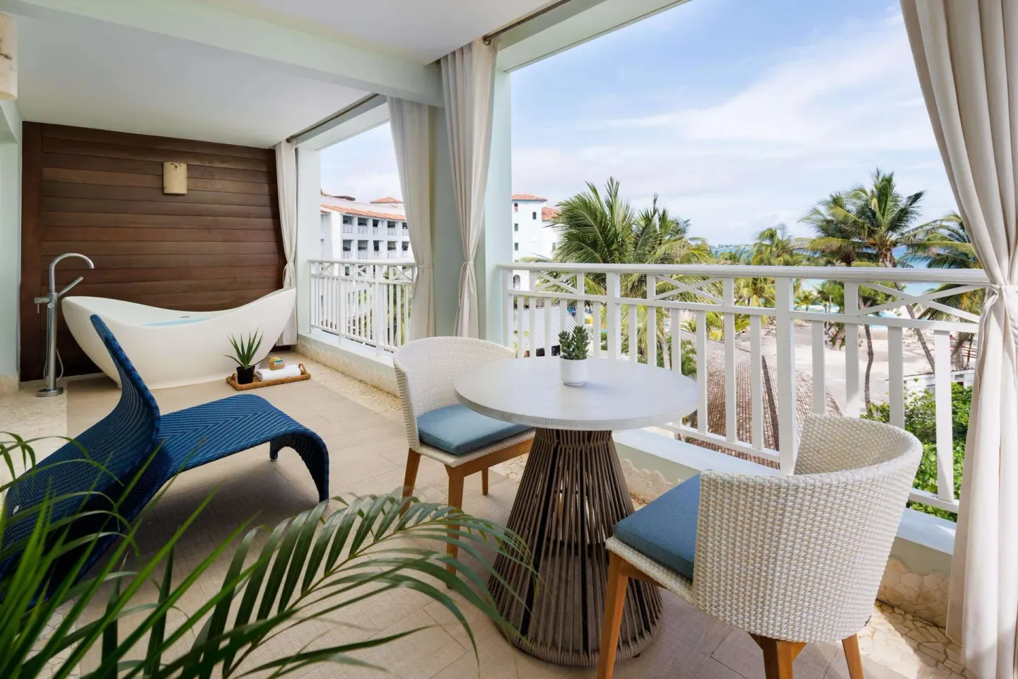 Suite balcony with soaking tub, lounge chair, table seating, and ocean view at Sandals Barbados.