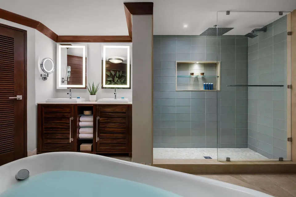 Suite bathroom with tub, double vanity, and glass-enclosed shower at Sandals Barbados.