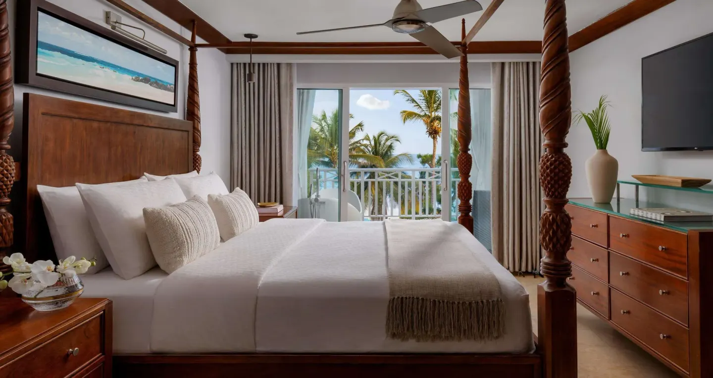 Ocean view suite bedroom with four-poster bed and balcony at Sandals Barbados.