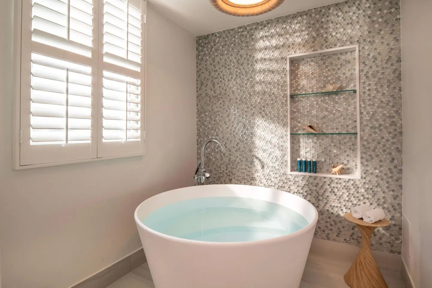 Freestanding soaking tub with mosaic wall and shutters at Sandals Dunns River.