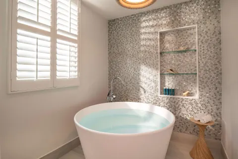 Freestanding soaking tub with mosaic wall and shutters at Sandals Dunns River.