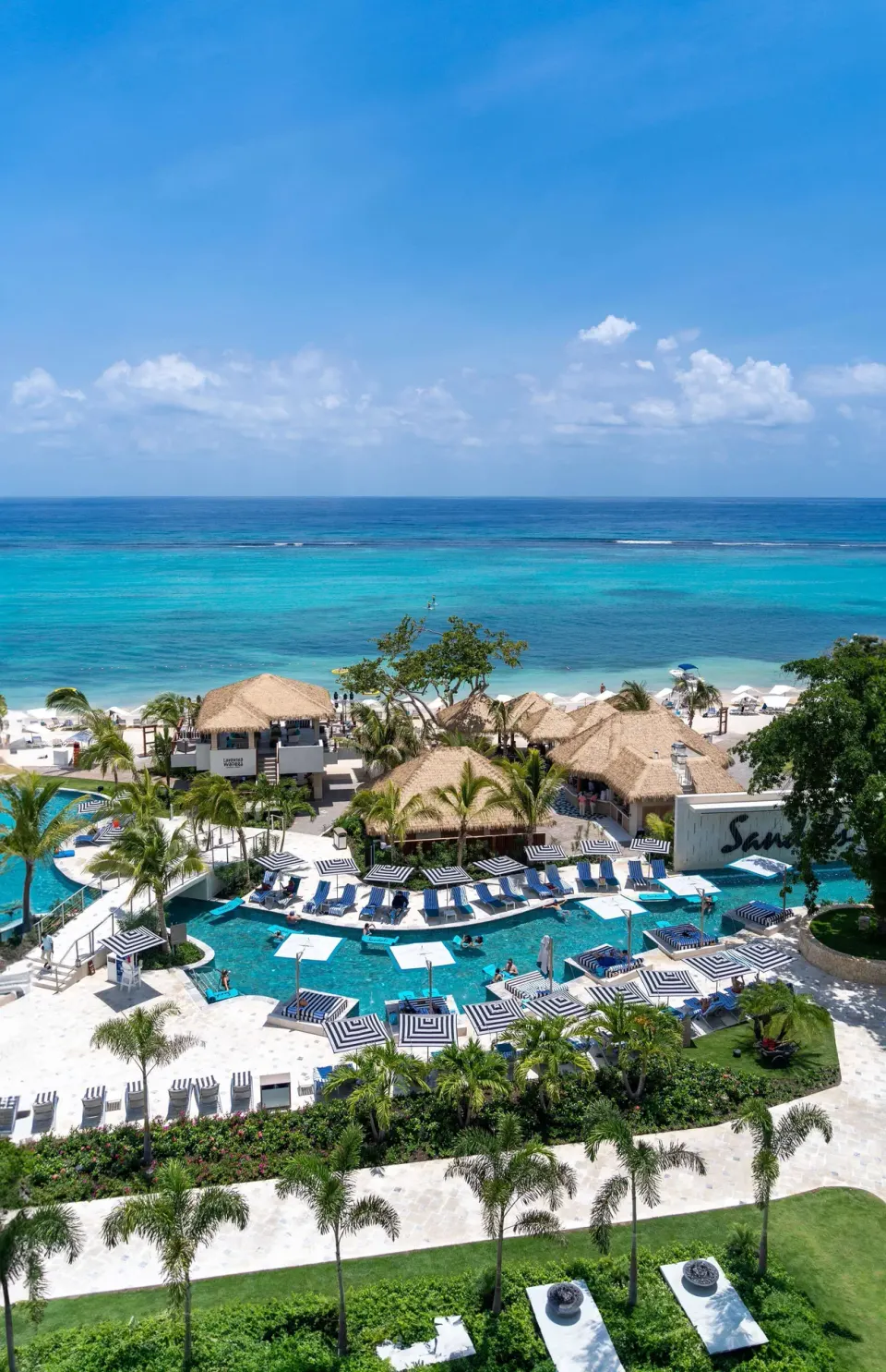 Aerial view of beachfront pools and turquoise sea at Sandals Dunns River.