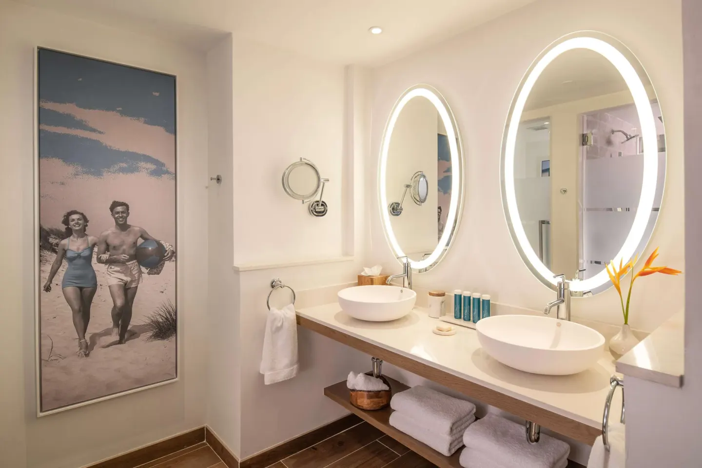 Double vanity bathroom with illuminated oval mirrors at Sandals Dunns River.