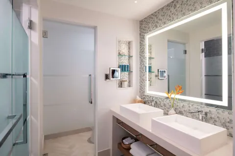 Double vanity bathroom with backlit mirror and shower at Sandals Dunns River.