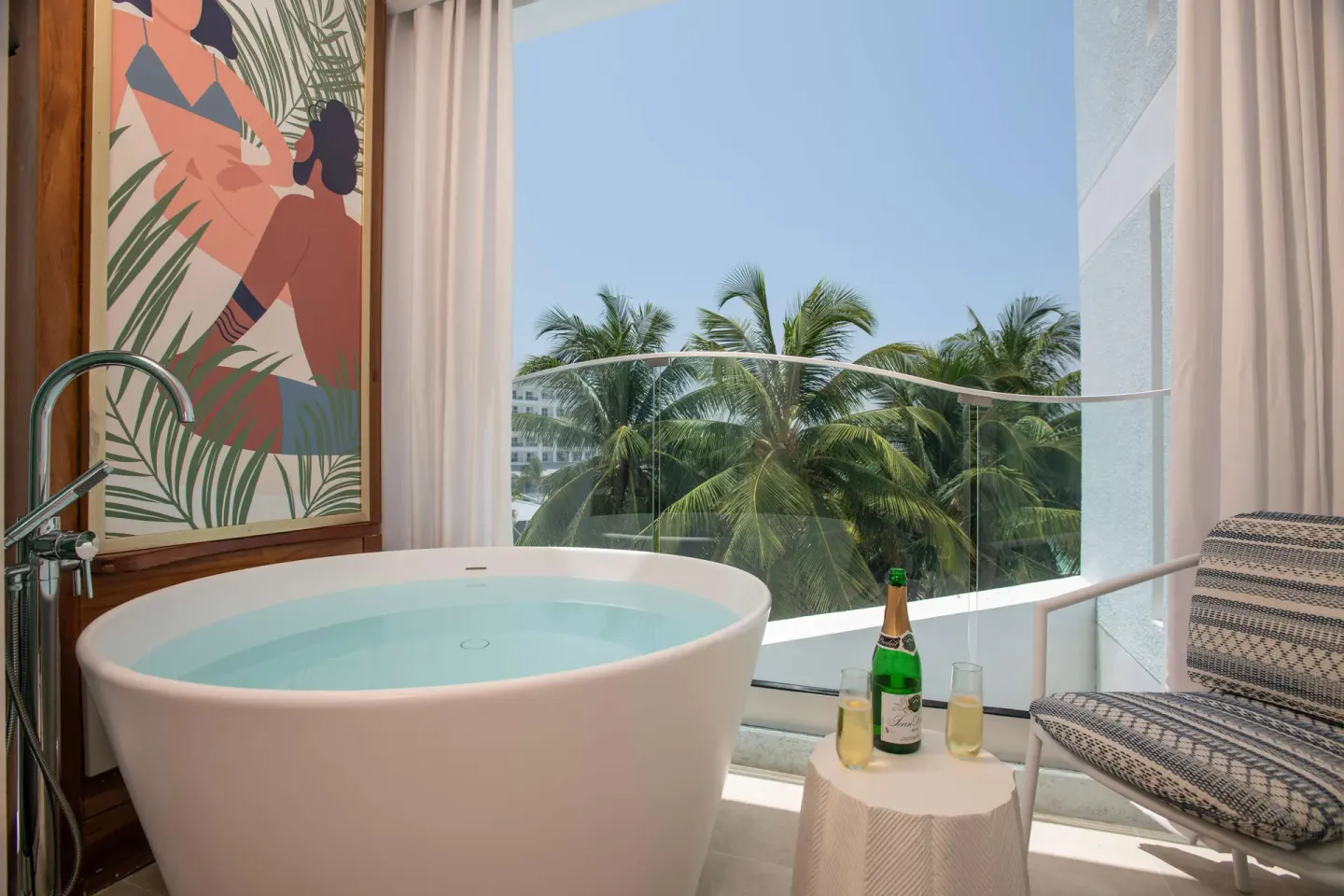 Indoor soaking tub by balcony doors with palm views at Sandals Dunns River.