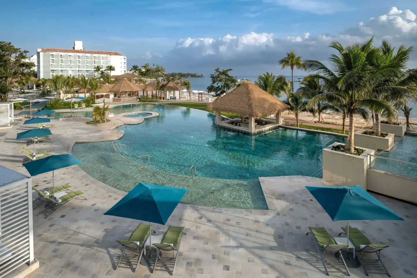 Quiet lagoon-style pool with palapa shade and palms at Sandals Dunns River.