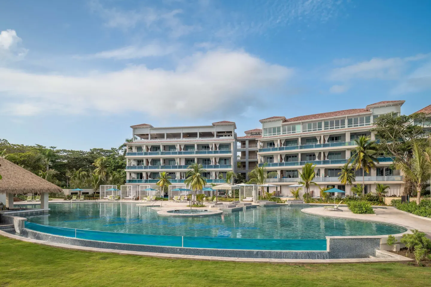 Main pool and room buildings at Sandals Dunns River under a blue sky.