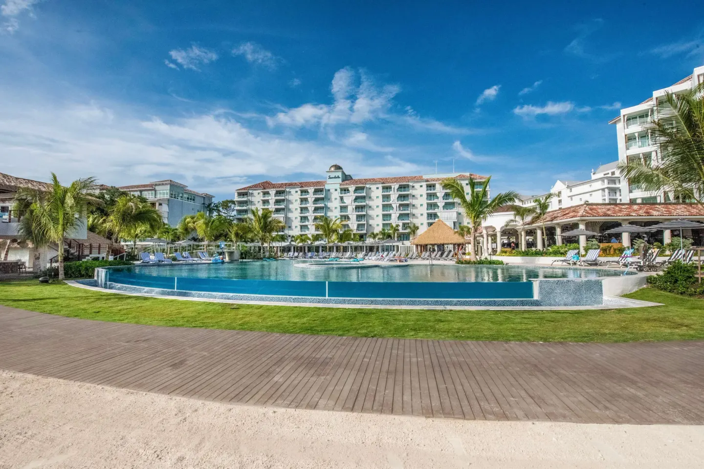 Wide pool view with lawn and resort buildings at Sandals Dunns River.