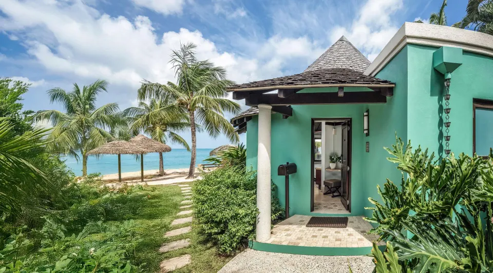 Beachfront villa entrance with palms and sea at Sandals Grande St. Lucian.