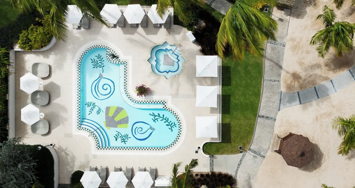 Aerial view of a decorative pool at Sandals Grande St. Lucian with umbrellas and beach paths nearby.