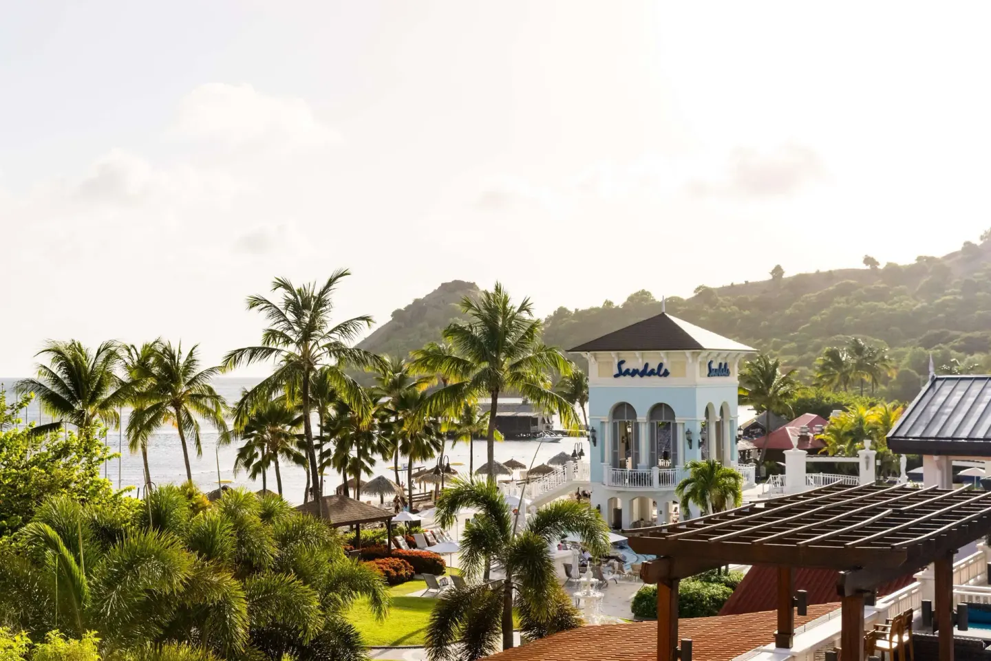 Elevated resort view with palms, beach and hillside at Sandals Grande St. Lucian.