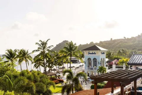 Elevated resort view with palms, beach and hillside at Sandals Grande St. Lucian.
