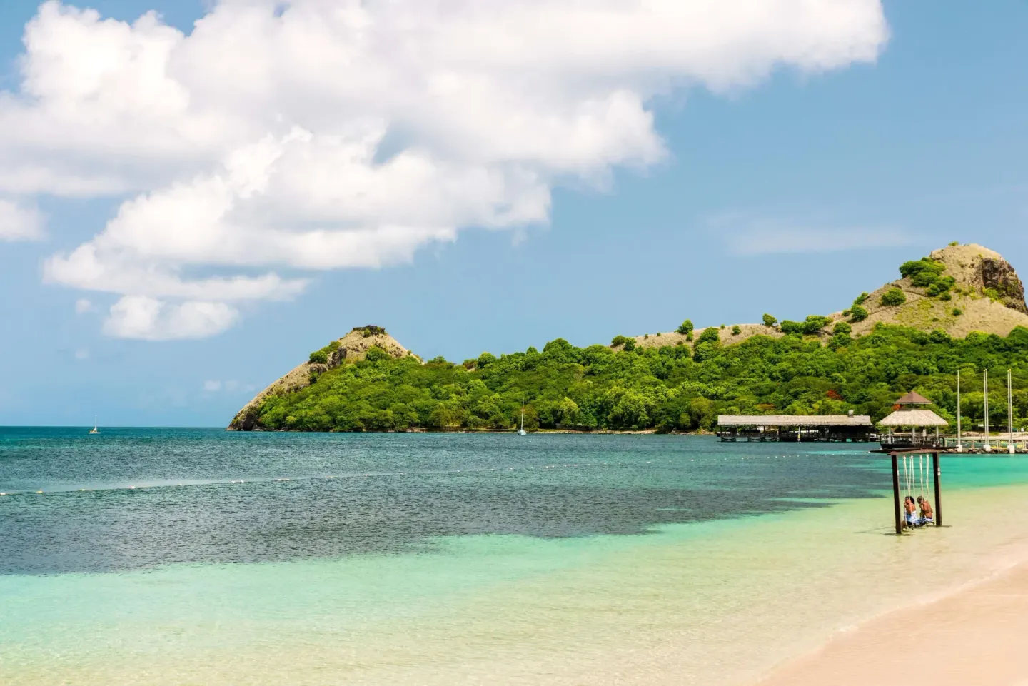 Quiet beach with clear water and green headland at Sandals Grande St. Lucian.
