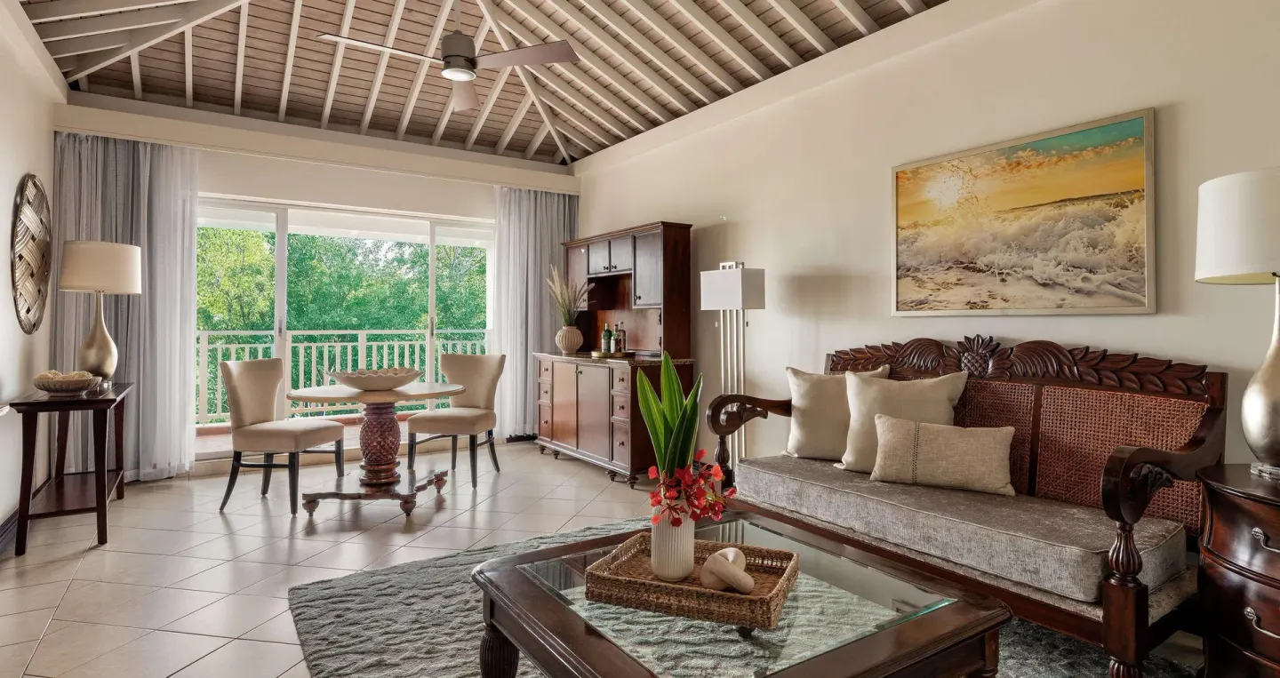 Living room with carved sofa and balcony doors at Sandals Grande St. Lucian.