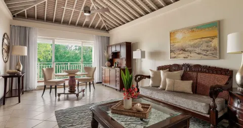 Living room with carved sofa and balcony doors at Sandals Grande St. Lucian.