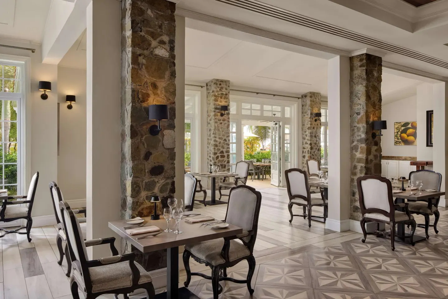Elegant dining room with stone columns and set tables at Sandals Grande St. Lucian.