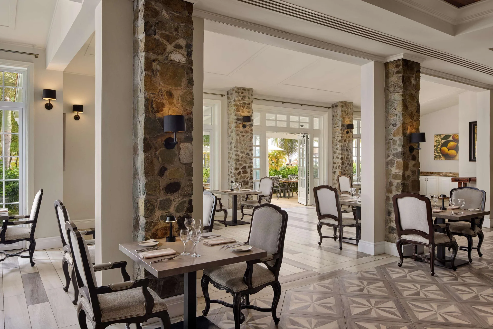 Elegant dining room with stone columns and set tables at Sandals Grande St. Lucian.