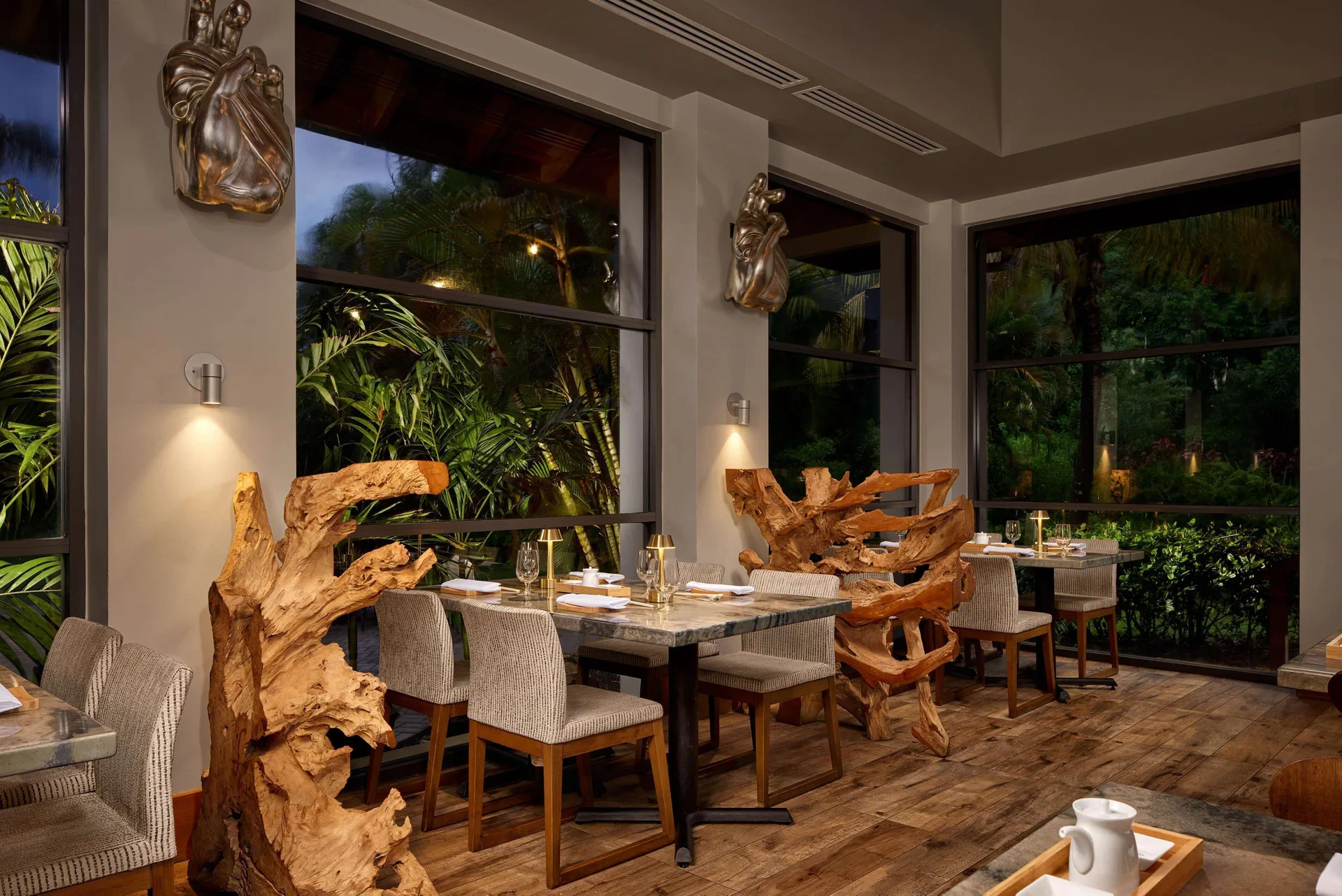 Restaurant dining room with wood sculptures and garden windows at Sandals Grande St. Lucian.