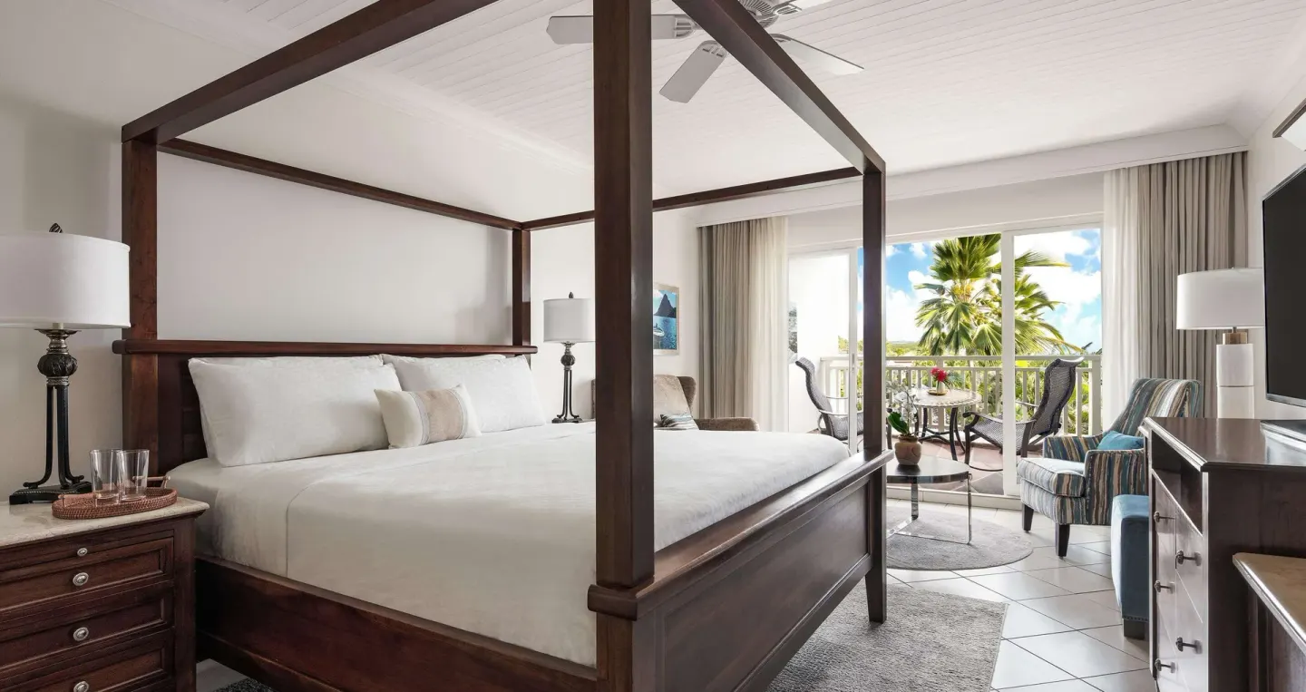 Club Room bedroom with four-poster king bed and balcony at Sandals Grande St. Lucian.
