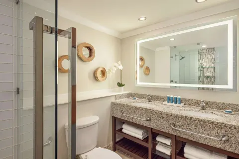 Club Room bathroom with double vanity and glass shower at Sandals Grande St. Lucian.