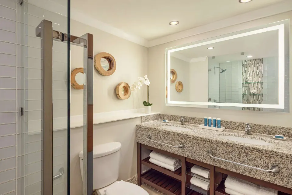 Club Room bathroom with double vanity and glass shower at Sandals Grande St. Lucian.