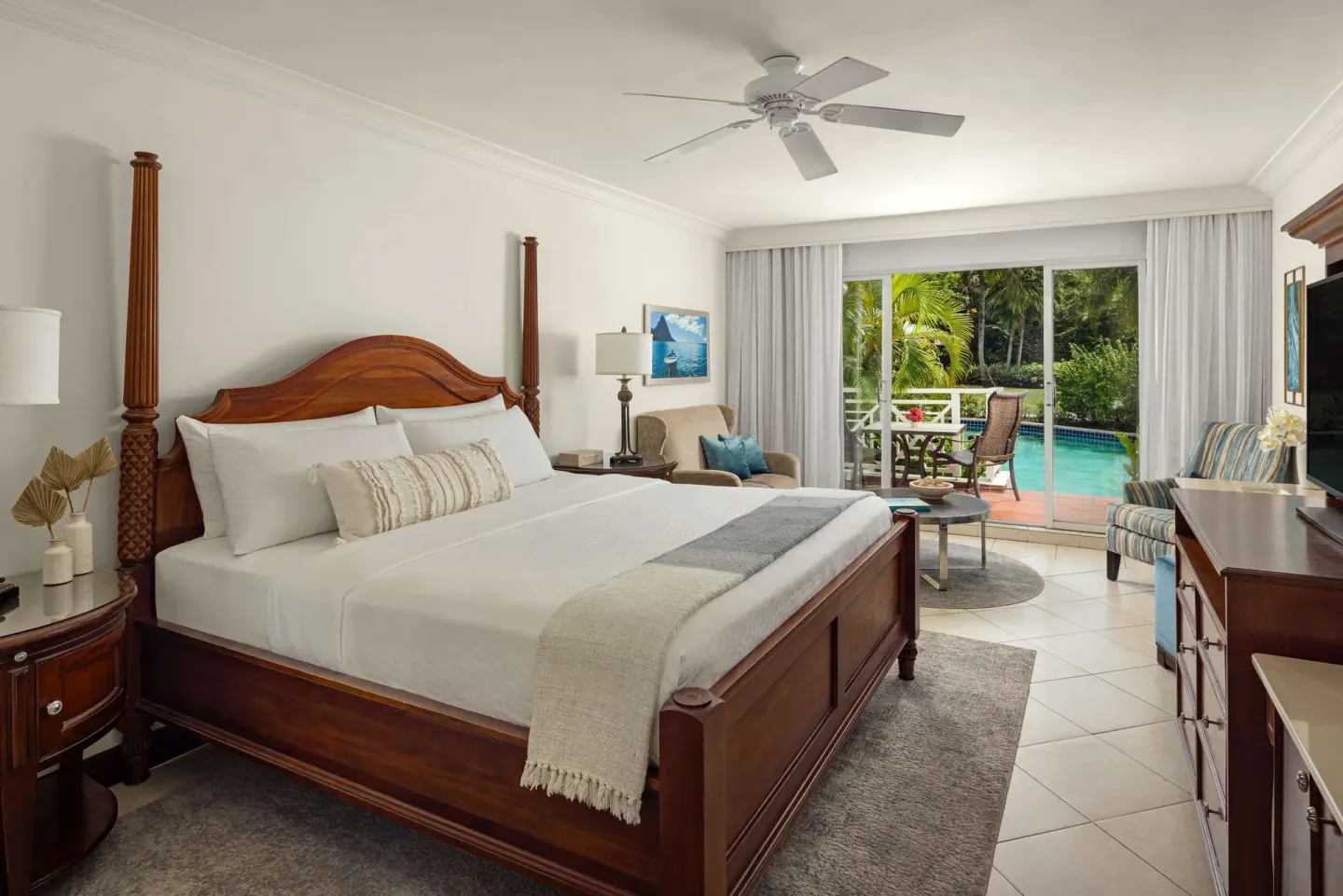 Club Room king bed and seating with pool-view patio at Sandals Grande St. Lucian.
