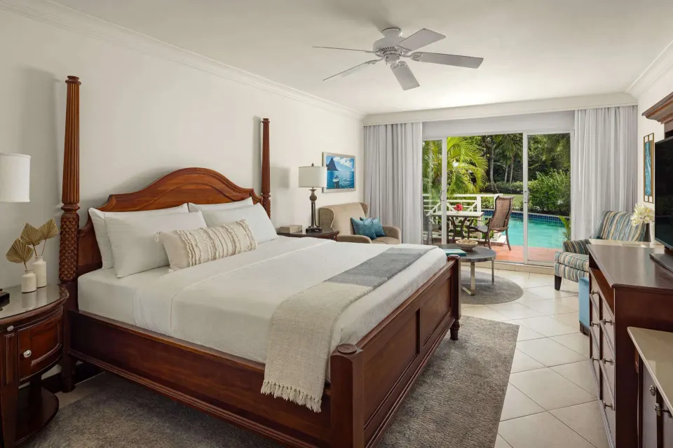 Club Room king bed and seating with pool-view patio at Sandals Grande St. Lucian.