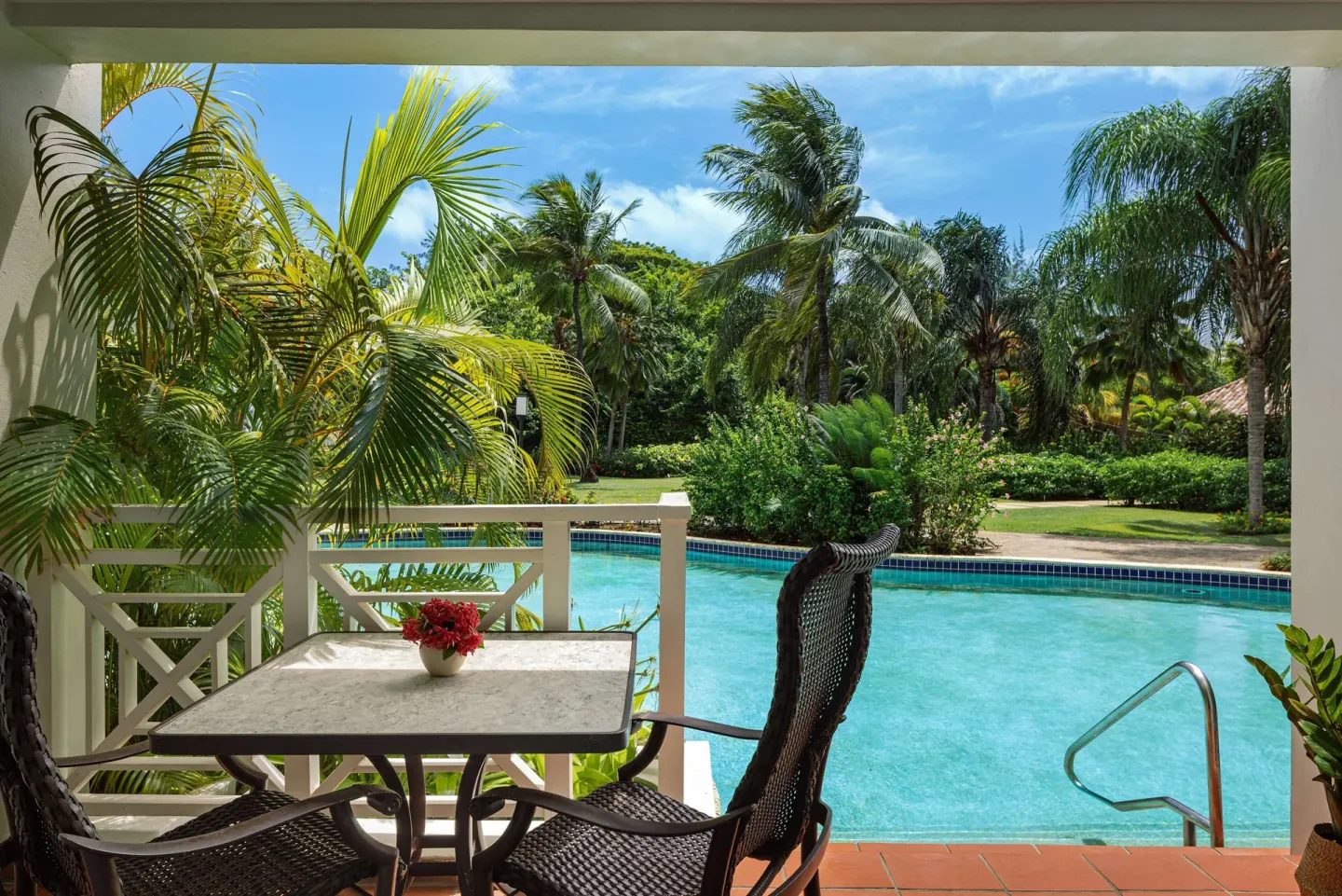 Pool-view patio with table, chairs, palms, and swim-up steps at Sandals Grande St. Lucian.