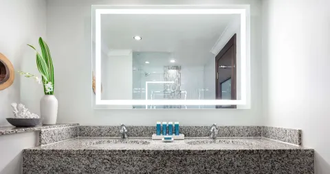 Bathroom vanity with illuminated mirror in a Deluxe room at Sandals Grande St. Lucian.