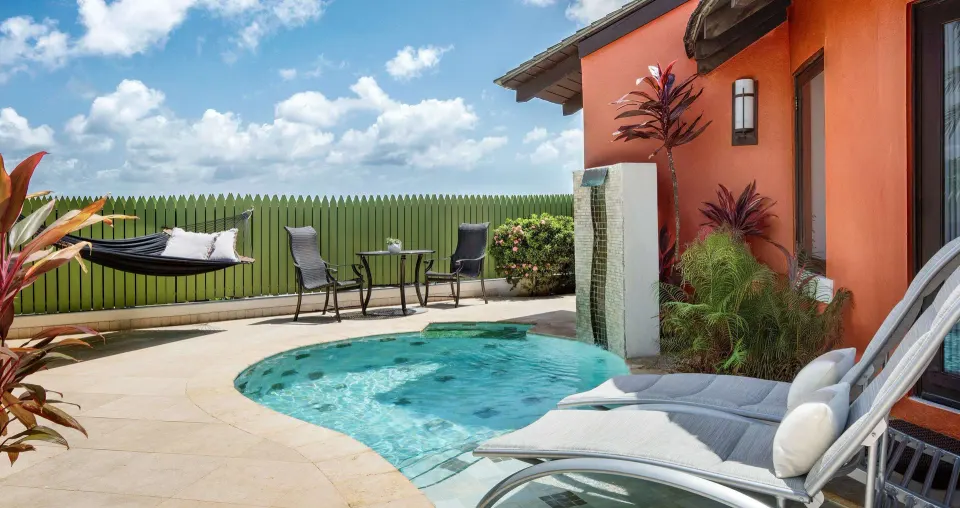 Private plunge pool patio of a luxury suite at Sandals Grande St. Lucian with loungers and hammock.