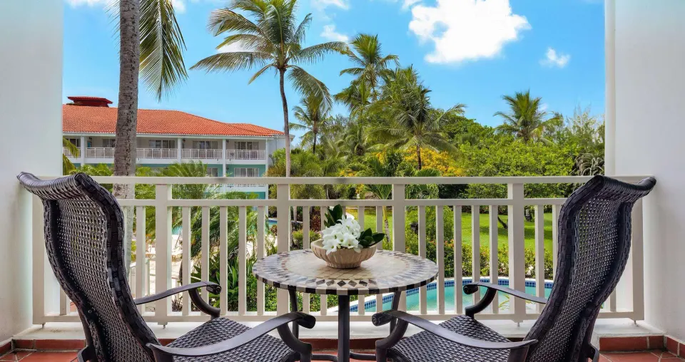 Furnished balcony with garden and pool views from a Premium Room at Sandals Grande St. Lucian.