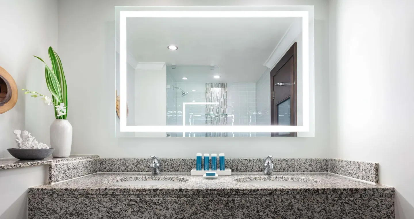 Granite double vanity and lit mirror in a Premium Room bathroom at Sandals Grande St. Lucian.