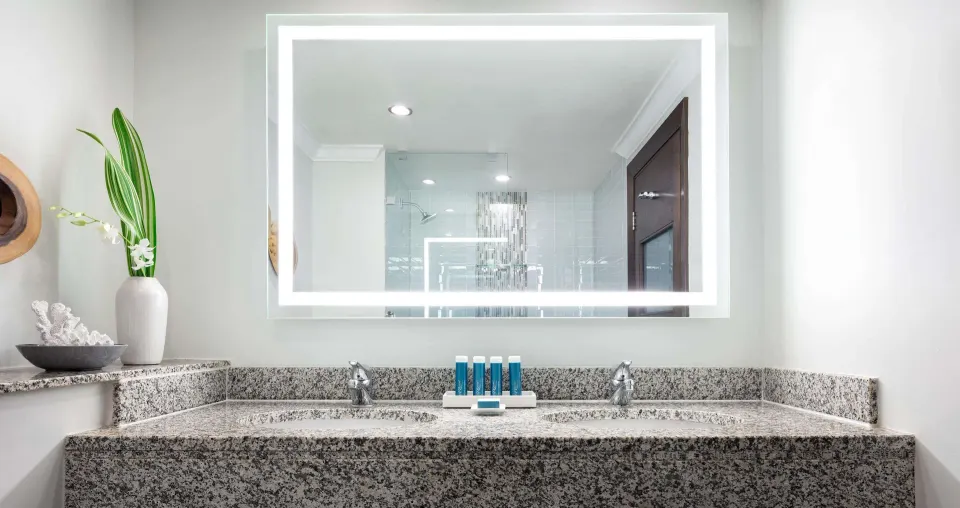Granite double vanity and lit mirror in a Premium Room bathroom at Sandals Grande St. Lucian.
