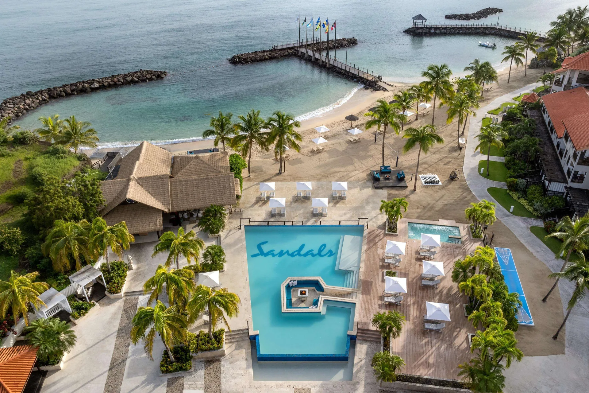 Aerial view of the beach, pool deck, pier, and shoreline at Sandals Grenada.