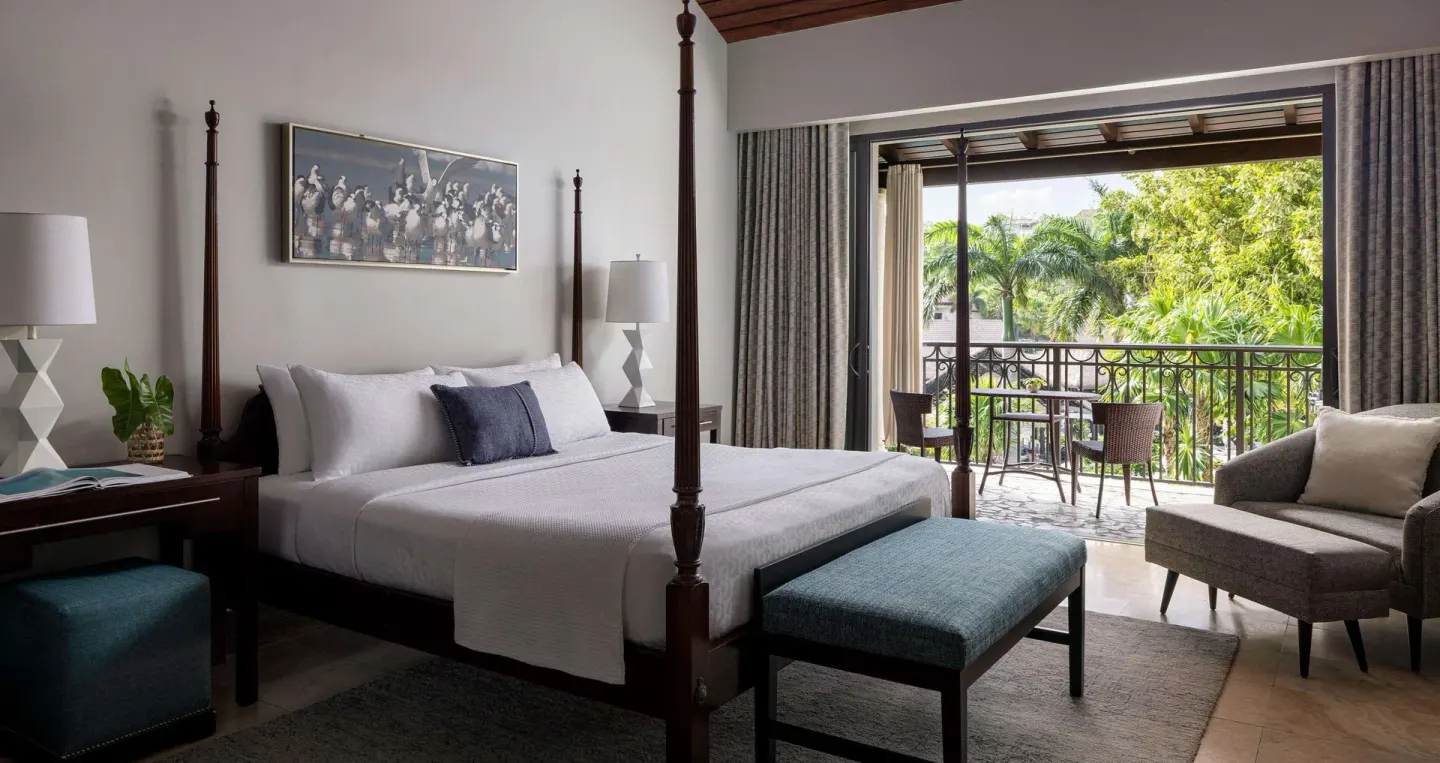 Four-poster king bed guest room with balcony view at Sandals Grenada.