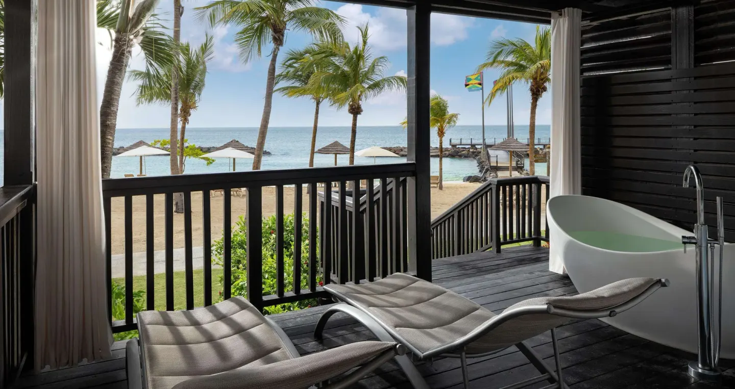 Beachfront balcony with loungers and a soaking tub overlooking the sea at Sandals Grenada.
