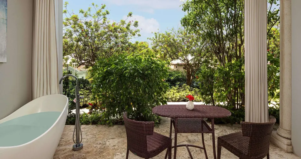 Garden patio with a soaking tub, table, and two chairs at Sandals Grenada.