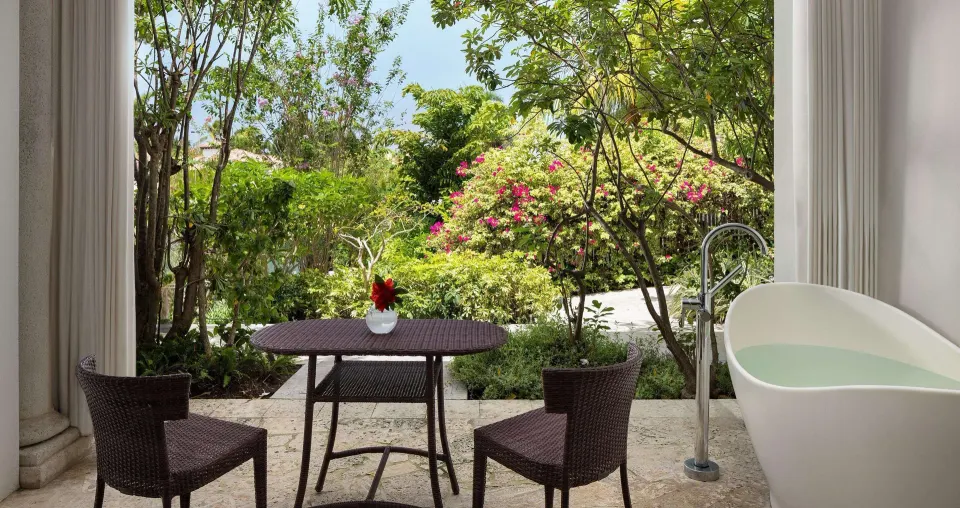 Private garden patio with table, chairs, and soaking tub at Sandals Grenada.